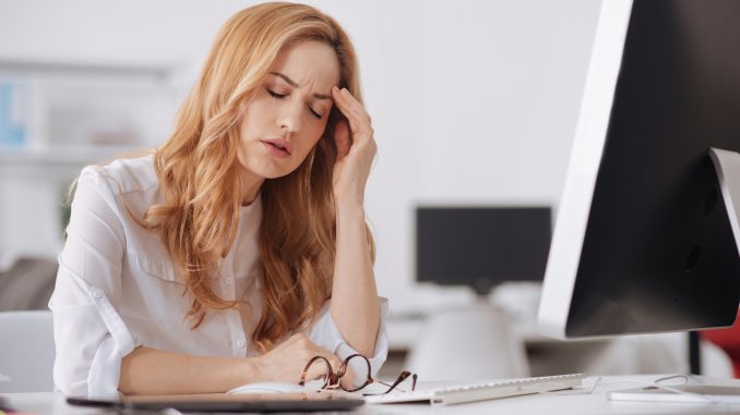 Exhausted manager suffering from chronic daily headaches in the office